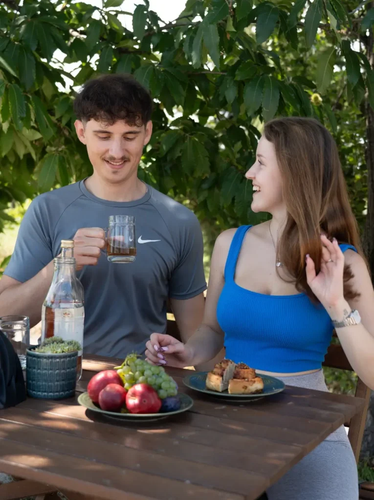 Junge Erwachsene genießen ein die Zeit im Freien mit Getränken und frischem Obst unter einem Baum.